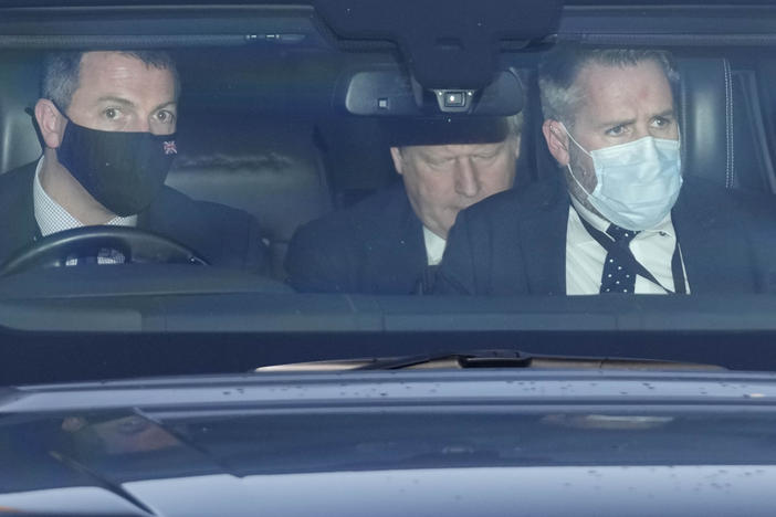 Britain's Prime Minister Boris Johnson, center, sits in a car as he leaves Parliament after attending the weekly Prime Ministers' Questions session in London, Wednesday, Jan. 12, 2022.