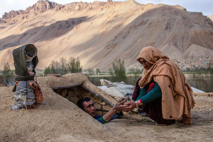 Roqia Qasqari, right, who lives in Gero village in Afghanistan's Bamyan Province, inspects potatoes stored from a previous harvest. Snow was scarce over the winter, raising fears of a severe drought in 2021.