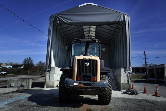 A tractor sits in front of a pile of salt used to create a brine that will help clear road of ice and snow ahead of a winter storm at the GDOT's Maintenance Activities Unit location on Friday, Jan. 14, 2022, in Forest Park, Ga.