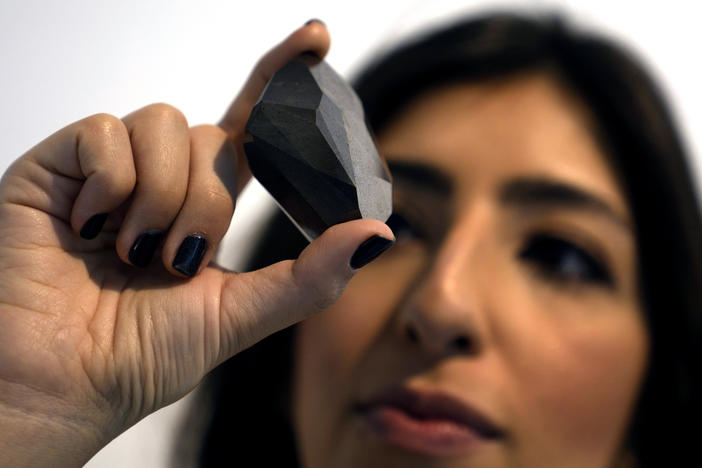 An employee of Sotheby's Dubai presents a 555.55 Carat Black Diamond called "The Enigma" on Monday that will be auctioned at Sotheby's Dubai gallery, in Dubai, United Arab Emirates.