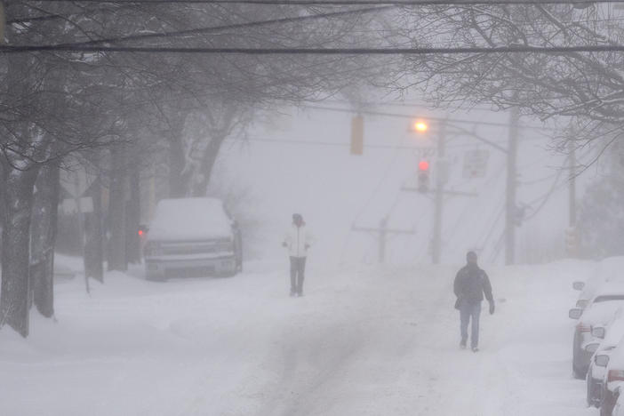 Pedestrians make their way down a partially plowed Murray Avenue Monday, Jan. 17, 2022, in Squirrel Hill neighborhood of Pittsburgh.