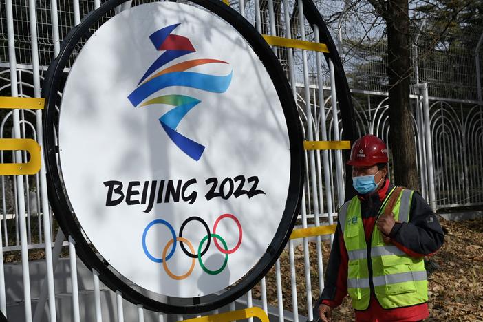 A construction worker walks past the Beijing 2022 Winter Olympic Games logo on a street in Beijing on December 11, 2021.
