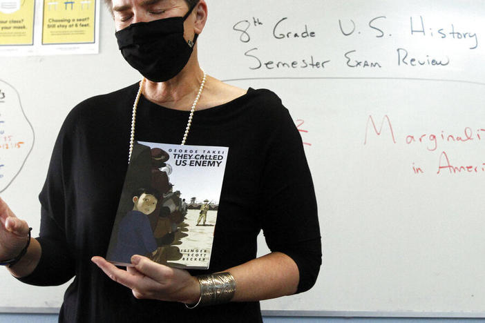 History teacher Wendy Leighton holds a copy of "They Called us Enemy," about the internment of Japanese Americans, while speaking about marginalized with her students at Monte del Sol Charter School, Friday, Dec. 3, 2021, in Santa Fe, N.M.