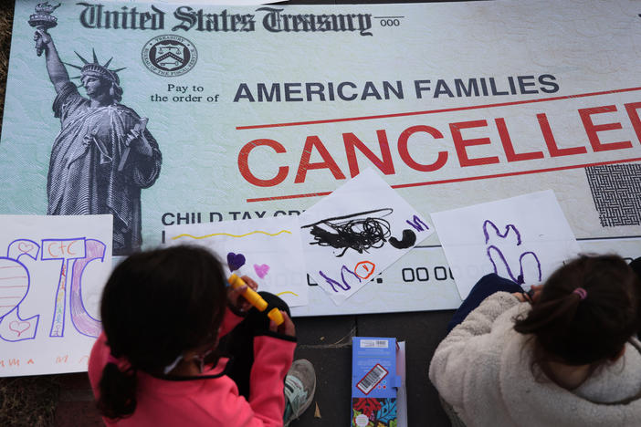 Children draw on top of a canceled check prop during a rally in favor of the child tax credit in front of the U.S. Capitol on Dec. 13, 2021, in Washington, D.C.