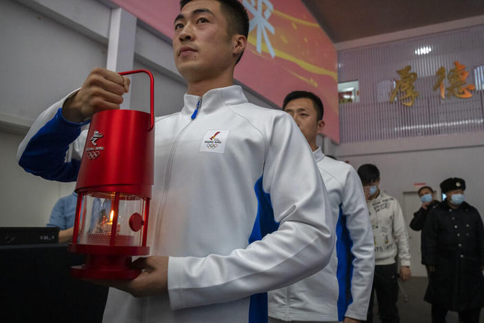 An official holds a lantern with the Olympic flame during an event to display the Olympic torch and flame at the Beijing University of Posts and Communications in Beijing, Thursday, Dec. 9, 2021.