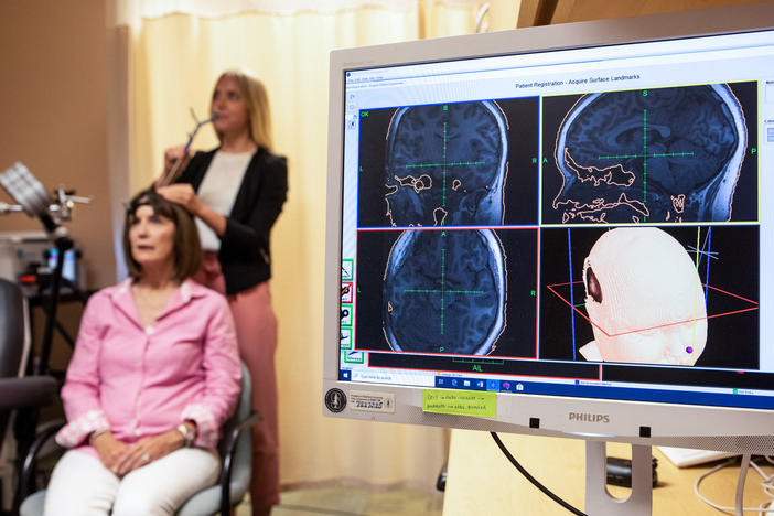 Eleanor Cole, Ph.D., demonstrates the treatment on trial participant Deirdre Lehman in May 2019 at the Stanford Brain Stimulation Lab.