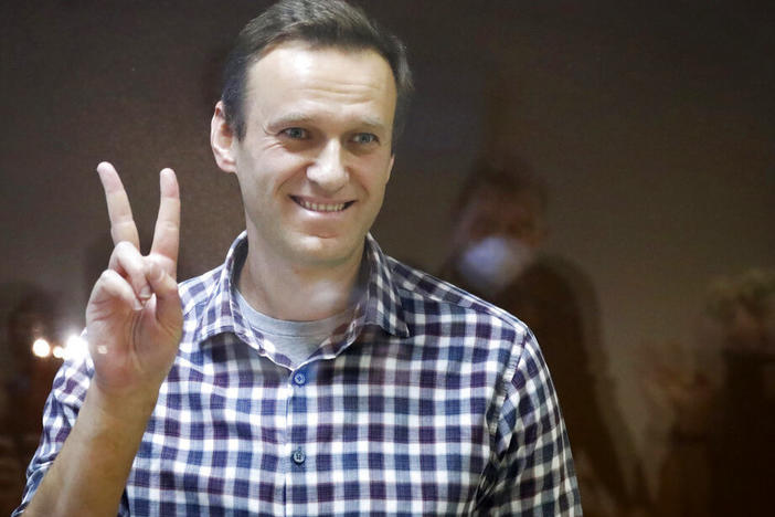 Russian opposition leader Alexei Navalny gestures as he stands in a cage in the Babuskinsky District Court in Moscow, Russia, Saturday, Feb. 20, 2021.