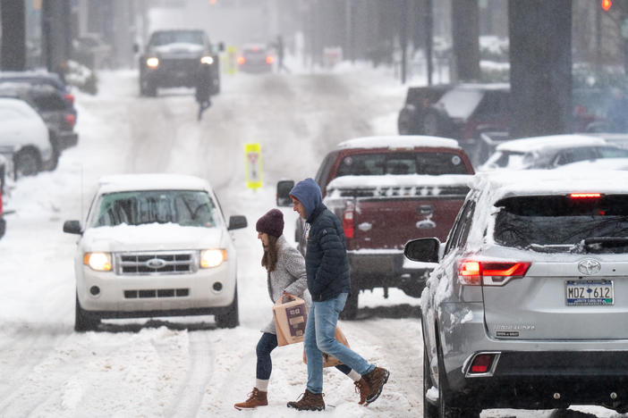 Pedestrians cross a street as motorists drive through the snow on Jan. 16 in Greenville, S.C.