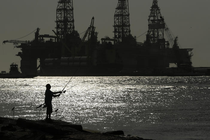 A man fishes near docked oil drilling platforms in 2020 in Port Aransas, Texas. A federal judge has revoked oil and gas leases sold in the Gulf of Mexico in November, saying the Interior Department did not take into account its impact on climate change.