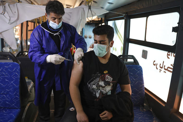 A man receives a COVID-19 vaccine at a mobile vaccine clinic bus at the Grand Bazaar of Tehran, Iran, Saturday, Jan. 22, 2022.