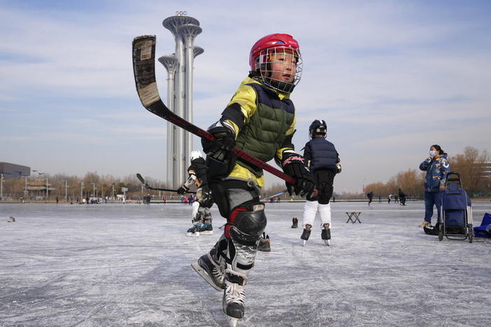 A child practices ice hockey near the Beijing Olympics Tower in Beijing, China, Tuesday, Jan. 18, 2022.