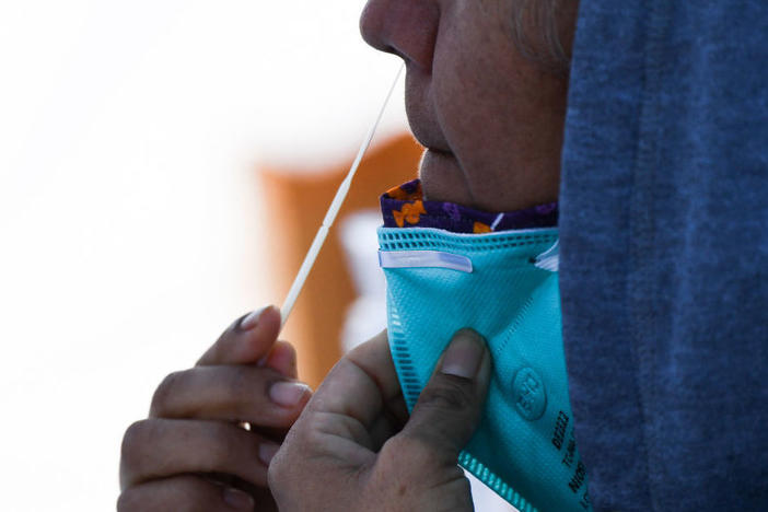 A person swabs their nose as they receive testing for both rapid antigen and PCR COVID-19 tests at a Reliant Health Services testing site in Hawthorne, Calif., on Jan. 18.