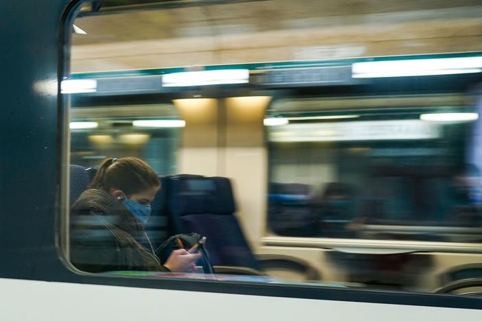 A commuter wearing a protective face mask looks at her mobile phone in a train arriving at the Central Train Station in Brussels in May 2020. Belgium's new rule addresses the ever-blurry line between work and personal life in the pandemic.