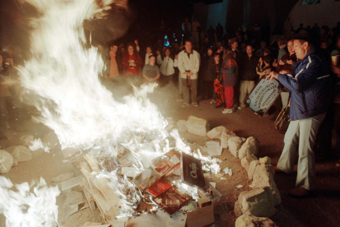 A woman tosses a Ouija Board into a bonfire outside a church in New Mexico in 2001, after  the church's pastor urged parishioners to burn dozens of Harry Potter books and other types of literature and games they found offensive.