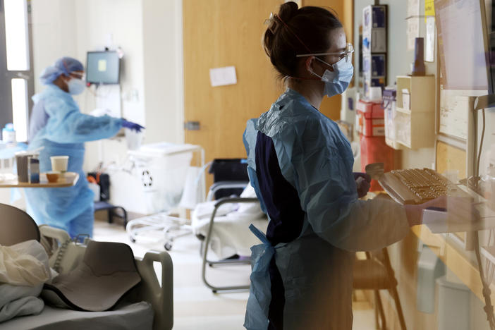 Nurse Elisa Gilbert checks on a patient in the acute care COVID-19 unit at Harborview Medical Center in Seattle on Jan. 21. The highly transmissible omicron variant of the coronavirus is putting a significant strain on health systems nationally, resulting in staffing shortages and changes in capacity strategies.