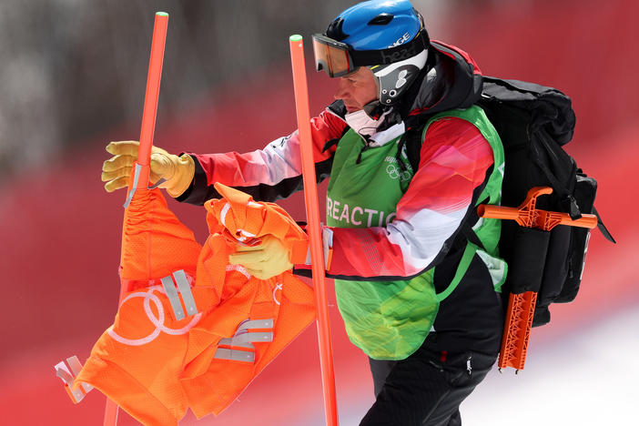 A courseworker removes a gate flag following the postponement of the men's downhill due to high winds on day two of the Beijing 2022 Winter Olympic Games at National Alpine Ski Center.