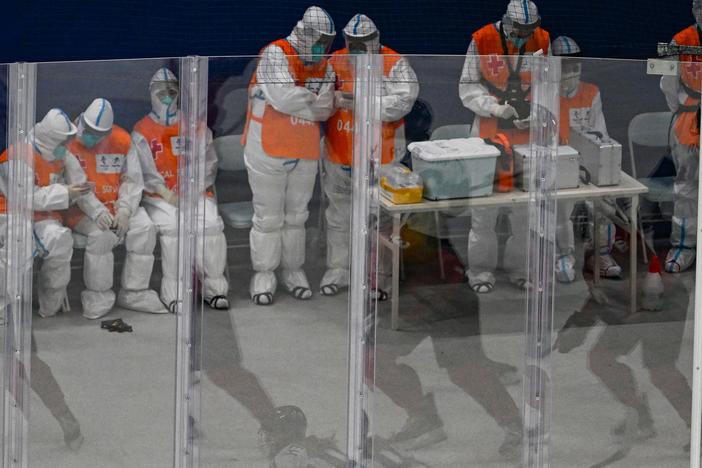 Medical personnel wearing personal protective equipment keep watch during a hockey game at the Beijing 2022 Winter Olympic Games.