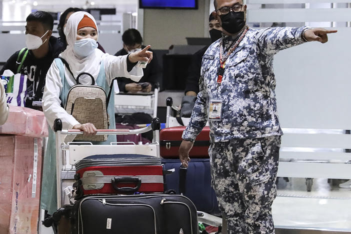 Members of the Philippine Coast Guard assist passengers as they arrive at Manila's International Airport. The Philippines lifted a nearly 2-year ban on foreign travelers Thursday as an omicron-fueled surge eases.