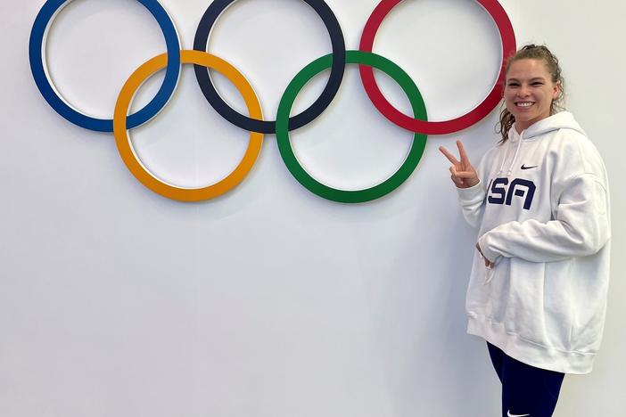 Kelly Curtis stands next to the Olympic rings. She's competing in the skeleton competition at the Beijing Olympics.