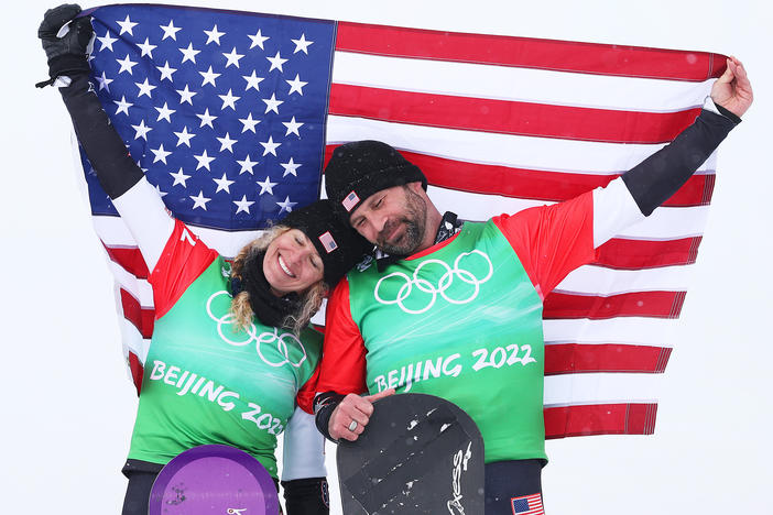 Gold medalists Lindsey Jacobellis (left) and Nick Baumgartner celebrate their win of the mixed team snowboard cross finals at the flower ceremony during the Beijing 2022 Winter Olympics on Feb. 12, 2022.