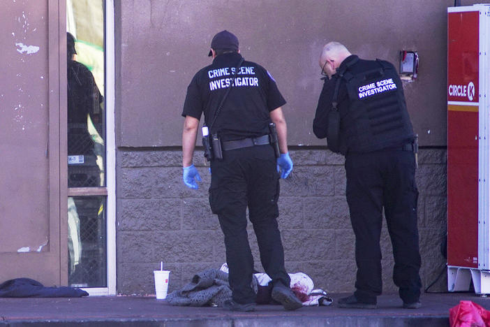 Albuquerque Police crime scene specialists photograph bloody articles of clothing after multiple people were stabbed on Sunday.