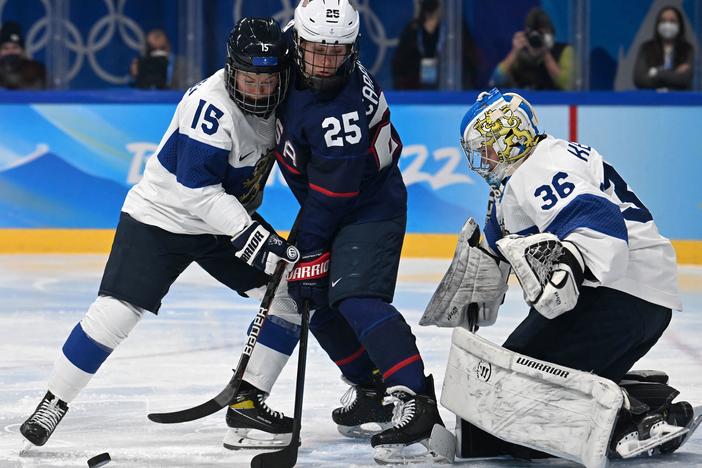 Finland's Minnamari Tuominen (left) and Team USA's Alexandra Carpenter vie for the puck next to Finland's goaltender Anni Keisala during the women's ice hockey semi-final match of the Beijing 2022 Winter Olympic Games.