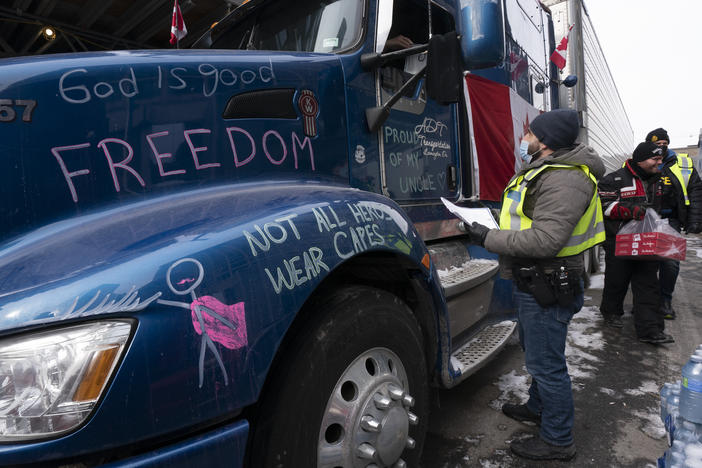 An officer speaks with a driver as police distribute notices to protesters on Wednesday. Police warned protesters that they could be subject to arrest and their vehicles seized as they tried to chase protesters out of the capital.