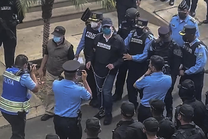 Police escort former Honduran President Juan Orlando Hernández, in handcuffs, from his house in Tegucigalpa after receiving an extradition order from the United States.