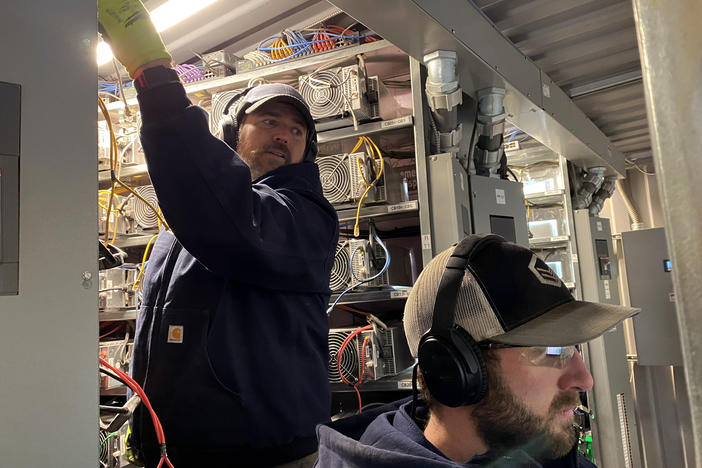 Workers install cryptocurrency mining computers inside a converted shipping container at the Compute North facility in Nebraska.