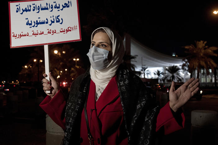 Mashael al-Shuwaihan, who sits on the board of Kuwait's Women's Cultural Society, speaks during an interview, at a protest outside Kuwait's National Assembly in Kuwait City on Feb. 7, 2022. Her placard reads: "Freedom and equality for women are constitutional pillars."