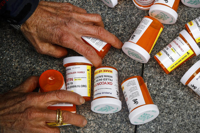 A protester gathers containers that look like OxyContin bottles at an anti-opioid demonstration in front of the U.S. Department of Health and Human Services headquarters in Washington, D.C., in 2019.