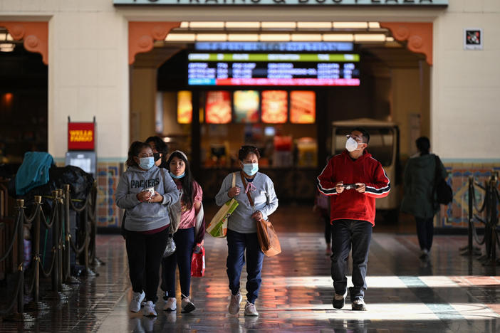 A family wearing face masks walks through Union Station in Los Angeles, California, January 5, 2022. With the Omicron variant driving a surge of Covid-19 cases, California announced January 5, 2022 that a statewide indoor mask mandate, due to expire on January 15, 2022, will be extended until at least February 15, 2022.