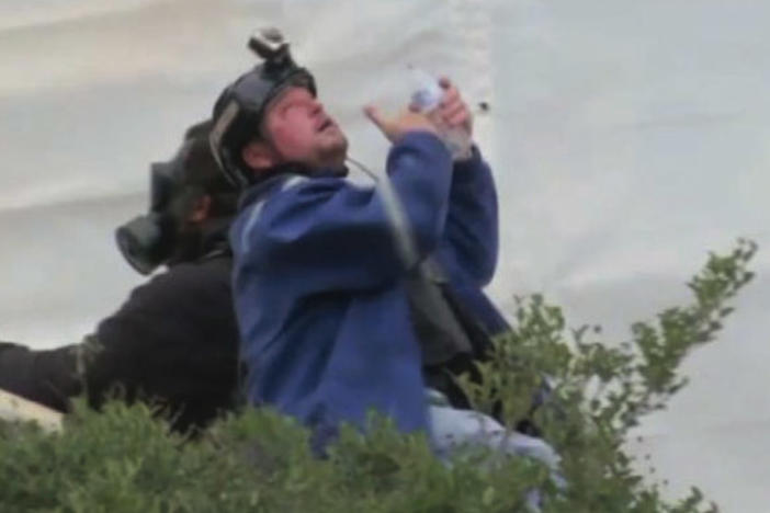 The U.S. government says in its affidavit that this photo shows Guy Reffitt rinsing his eyes outside the Capitol on Jan. 6, 2021, wearing a blue jacket over a tactical vest and a helmet with a camera.