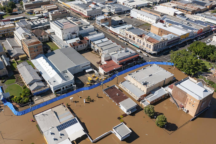 In this photo provided by the Fraser Coast Regional Council, a blue barrier helps hold back flood water in a section of Maryborough, Australia on Tuesday.