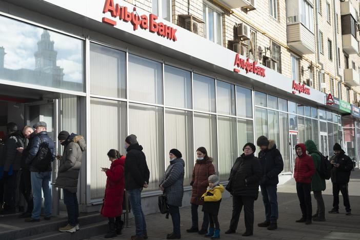 People stand in line to withdraw money from an ATM of Alfa Bank in Moscow on Sunday. Russians flocked to banks and ATMs shortly after Russia launched an attack on Ukraine and the West announced severe sanctions.