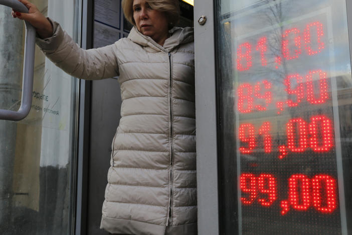 A woman leaves a Moscow exchange office with a screen showing the currency exchange rates of the U.S. dollar and the euro to Russian rubles on Feb. 24.