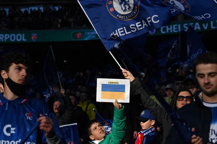 Chelsea supporters hold up Ukrainian flags in the crowd ahead of the English League Cup final football match between Chelsea and Liverpool at Wembley Stadium, north-west London on February 27, 2022. Russian billionaire Roman Abramovich handed over control of Chelsea to trustees of its charitable foundation on Saturday as Premier League players showed their support for war-torn Ukraine.