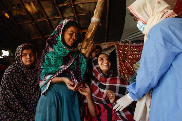 Young women wait to get vaccinated by Namra, a 21-year-old health worker who's part of a national door-to-door vaccination effort in the informal Hindubasti settlement in Karachi.