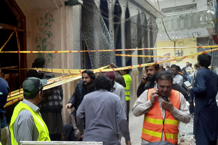 Rescue workers and volunteers gather at the site of bomb explosion in Peshawar, Pakistan, on Friday.