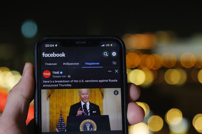 Russia blocked Facebook on Friday citing "discrimination" against state-sponsored media. Here, a smartphone user in Moscow watches a Facebook clip of President Biden on Feb. 25.
