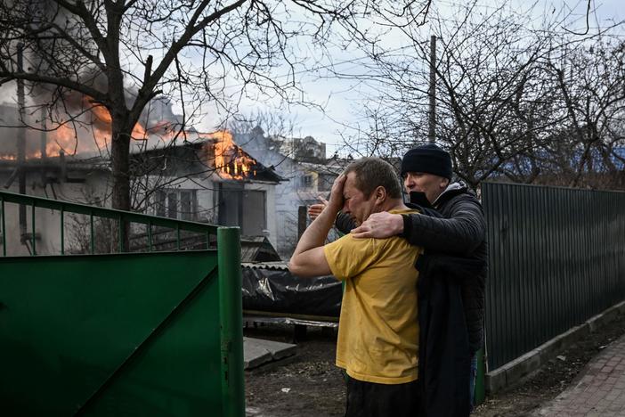 Yevghen Zbormyrsky, 49, is comforted as he stands in front of his burning home after it was shelled in the city of Irpin, outside Kyiv, Ukraine, on Friday. The U.N. Human Rights Council overwhelmingly voted to create a top-level investigation into violations committed following Russia's invasion of Ukraine.