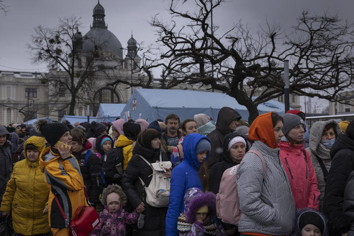 Families wait to make their way from the main bus and train terminal on Saturday in Lviv, Ukraine. More than 1 million people have fled Ukraine following Russia's assault on the country, with many Ukrainians passing through Lviv on their way to Poland.