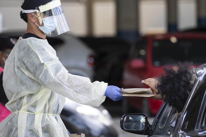 A health worker gives out rapid COVID-19 antigen self-test kits at the Waipareira Trust drive-in COVID-19 testing station in Auckland, New Zealand, on Tuesday.