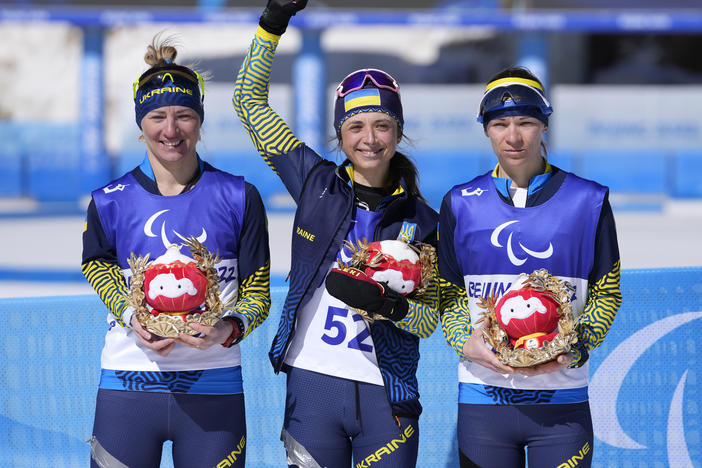 Gold medalist Iryna Bui (center) silver medalist Oleksandra Kononova (left) and bronze medalist Liudmyla Liashenko celebrate after the women's biathlon middle distance standing event at the 2022 Winter Paralympics on Tuesday.