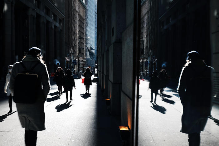 People walk along Wall Street near the New York Stock Exchange, in New York City. The stock market has been volatile as the war in Ukraine and high oil prices continues to worry investors. Americans' stress about global uncertainty is high, according to a new survey.