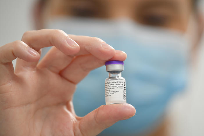 A staff member poses with a vial of Pfizer-BioNTech COVID-19 vaccine at a vaccination health center.