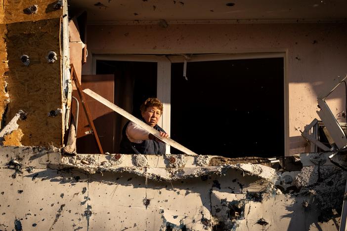 A resident cleans her balcony in an apartment building damaged by shelling in Kyiv on Tuesday.