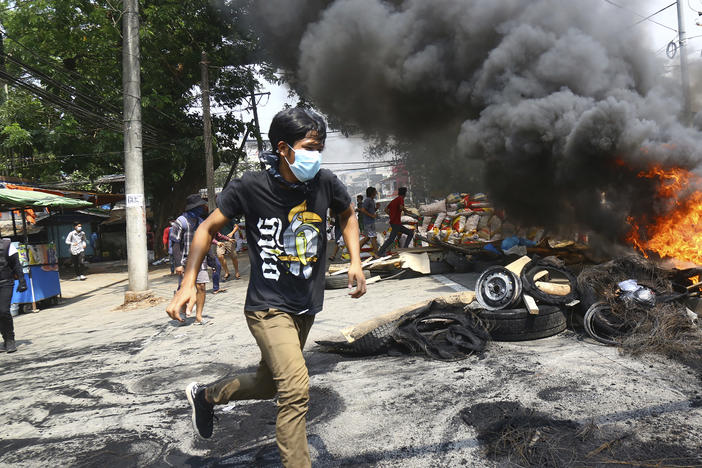 Anti-coup protesters are shown running around their makeshift barricade as they make a defense line during a demonstration in Yangon, Myanmar, on March 28, 2021.