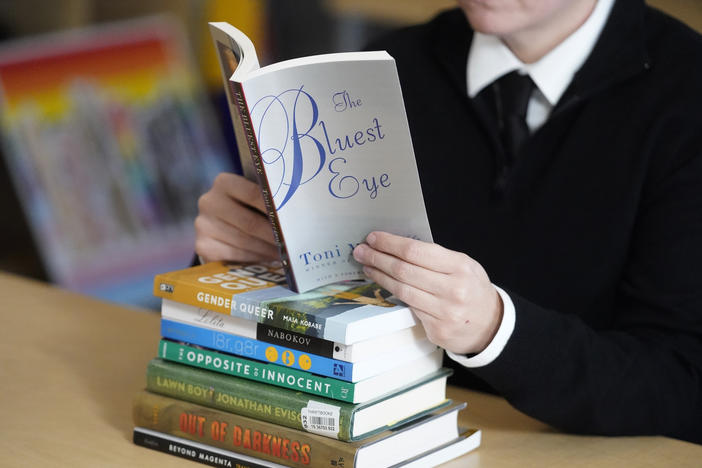 Amanda Darrow, director of youth, family and education programs at the Utah Pride Center, poses with books, including <em>The Bluest Eye</em>, by Toni Morrison and<em> Lawn Boy</em> by Jonathan Evison, that have been the subject of complaints from parents in Salt Lake City on Dec. 16, 2021.