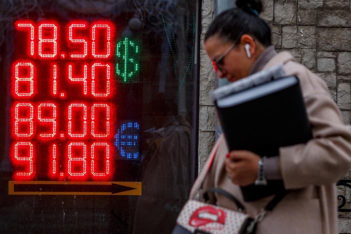 A woman walks past a display showing currency exchange rates of the U.S. dollar and the euro against the Russian ruble in Moscow on Feb. 22. Russia owes over $100 million in interest payments for two bonds on Wednesday as fears grow that the country will default on its debt.